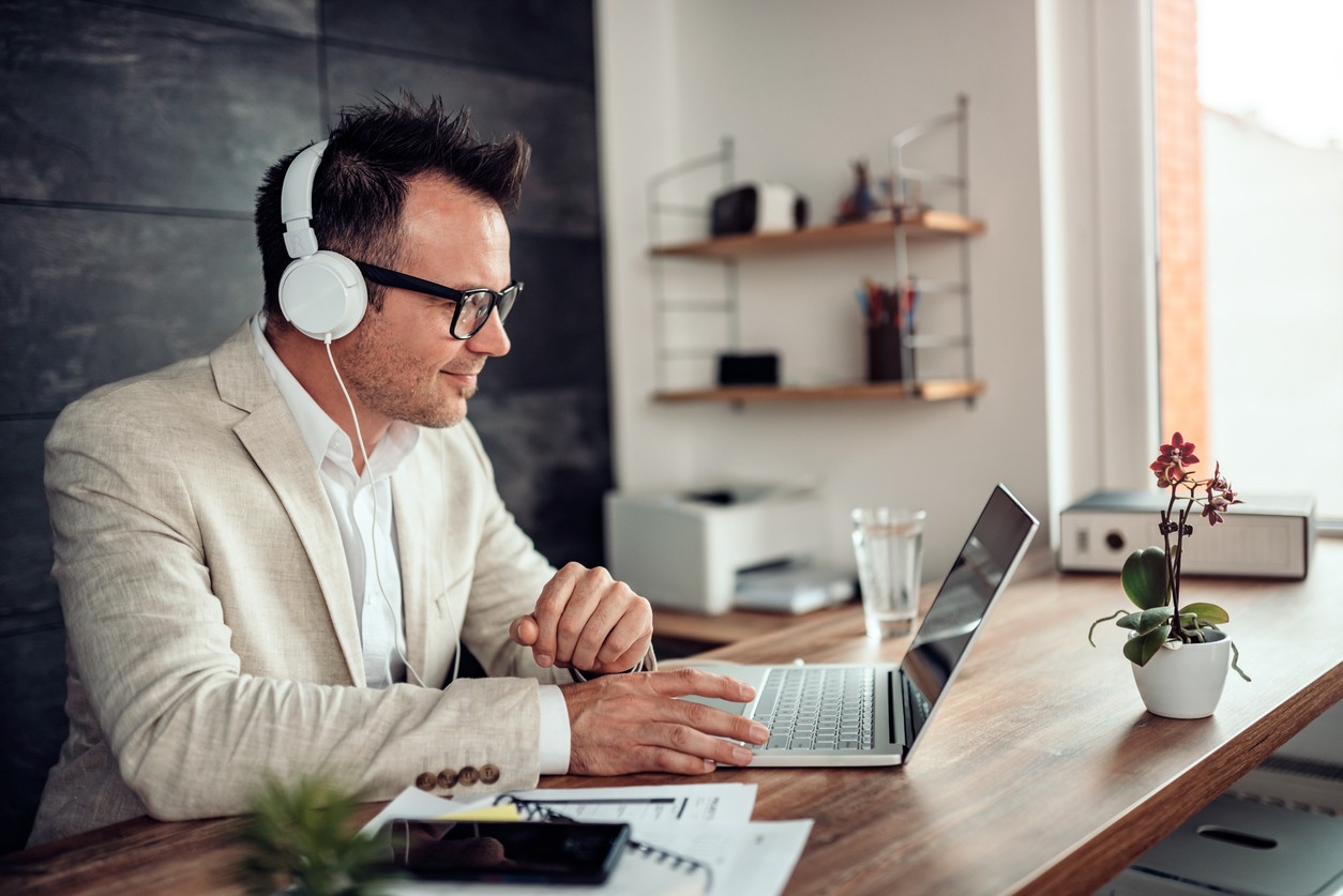 Businessman using laptop and listening music on headphones